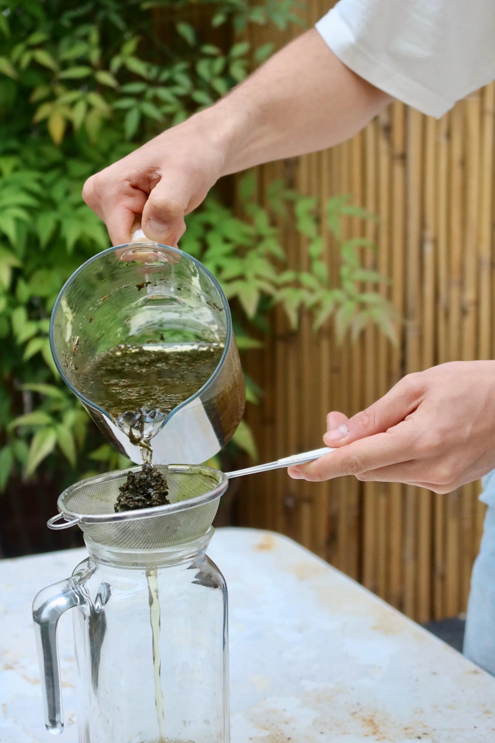 Tè filtrato e versato in una caraffa di vetro in giardino